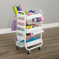 a white cart filled with craft supplies on top of a hard wood floor