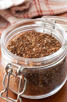 a glass jar filled with spices sitting on top of a wooden table