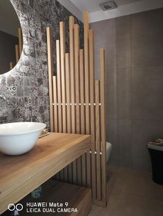 a bathroom with a sink, mirror and wooden slats on the wall behind it