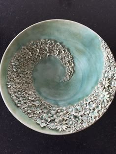 a blue bowl sitting on top of a black table next to a white plate with silver decorations