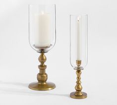 two glass candlesticks sitting next to each other on top of a white surface