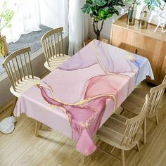 a dining room table covered with pink and gold cloths, next to a potted plant