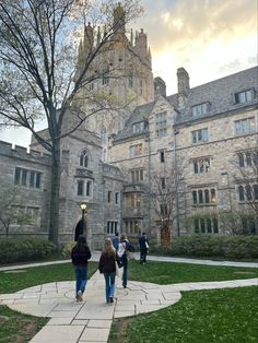 several people walking in front of a large building with trees and grass on the ground