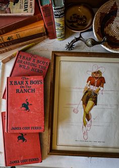 some old books are sitting on a table next to a framed drawing and other items