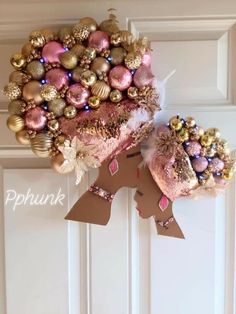 a wreath with ornaments hanging from it's side on the front door, next to an ornament