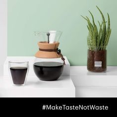 a coffee pot and two glasses on a counter top with a green wall in the background