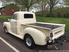 an old white pickup truck parked in a parking lot