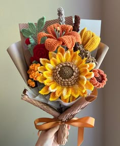 a hand holding a bouquet of crocheted flowers