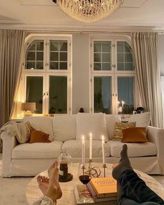 a person laying on the floor in front of a living room with chandelier