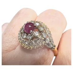 This Art Deco-style ring from the 1920-1925 period is crafted in 18K gold with platinum accents and features Diamonds and a ruby cabochon. It has a weight of 4.12 grams and is sized 15.5/55.5. The Diamonds are simple-cut, totaling 0.90 carats, and are of SI-VS clarity and H-G color grade. The other gemstone is a ruby cabochon weighing 0.80 carats. The ring measures 2.2 cm in length and 1.5 cm in width. The gemstones are set in claw settings. **IN STOCK** Characteristics: Material: 18K Gold with Antique Diamond Cabochon Rings, Vintage Diamond Cabochon Rings, Vintage Diamond Rings With Cabochon, Art Deco Cabochon Ring For Anniversary, Antique Ruby Diamond Ring Hallmarked, Vintage Hallmarked White Gold Ruby Ring, Hallmarked Vintage White Gold Ruby Ring, Hallmarked Oval Ruby Ring In Art Deco Style, Art Deco Hallmarked Oval Ruby Ring