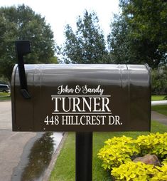 a mailbox with the number 121 on it in front of some flowers and trees