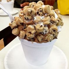 a cup filled with chocolate chip cookies and marshmallows on top of a white plate