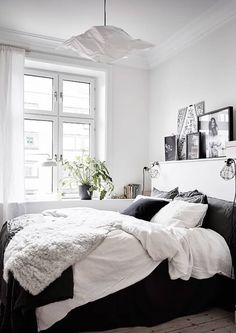 a bedroom with white walls, black and white bedding and pictures on the wall