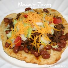 a white plate topped with a taco covered in beans and cheese on top of it