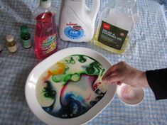 a person is painting something in a bowl on a table with other items around it