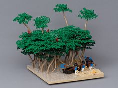 a lego model of a tree with people standing around it on a table next to the trees