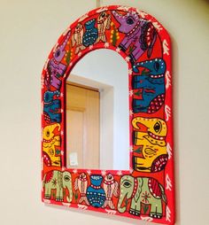 a mirror that is on the wall with an elephant pattern painted on it and hanging from a hook