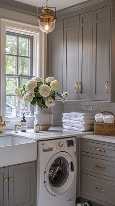 a washer and dryer sitting in a kitchen next to a window with flowers