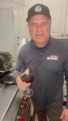 a man standing in a kitchen holding a glass of wine