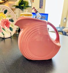 a pink vase sitting on top of a table next to other plates and bowls with flowers painted on them