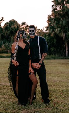 a man and woman in skeleton makeup posing for a photo with their faces painted black