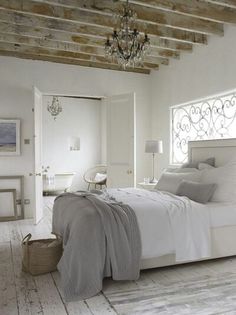 a bedroom with a bed, chandelier and white furniture in it's center