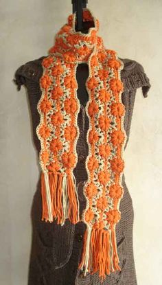 an orange and white crocheted scarf hanging on a wall