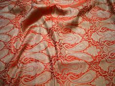 an orange and white paisley print fabric with red trims on the bottom half of it