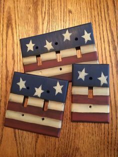 three wooden american flags are sitting on a wood table with holes in the middle to put them together