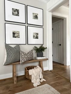 a wooden bench sitting in front of four framed pictures on the wall next to a door