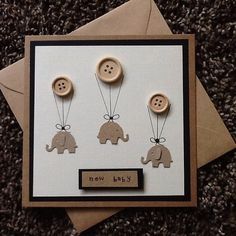 a card with three buttons and two elephants attached to the front of it, which says new baby