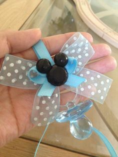 a hand holding a blue and white bow with two black beads on it's side