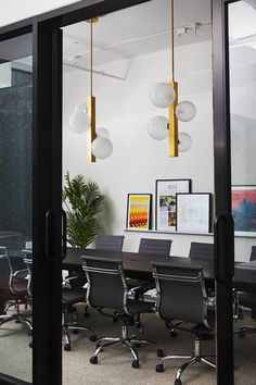 an empty conference room with chairs and pictures on the wall behind glass doors that lead to a meeting area