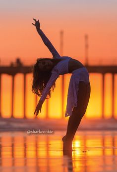 a woman doing yoga on the beach at sunset