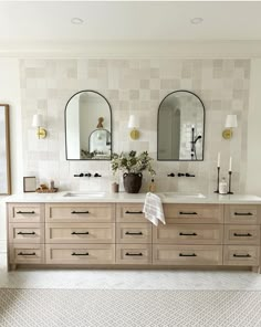 a bathroom with two sinks and mirrors on the wall next to each other in front of an area rug