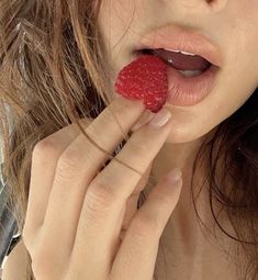 a woman holding a raspberry in her mouth