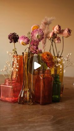 several vases filled with different types of flowers on top of a wooden table next to each other