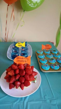 some strawberries and cupcakes are on a table