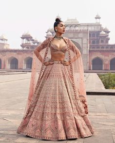 a woman in a pink lehenga with an intricate blouse and matching dupatta