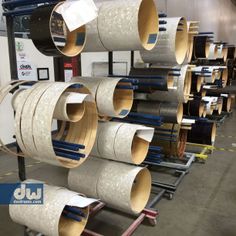 several rolls of different colors and sizes of paper on a rack in a factory room