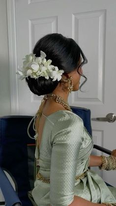 a woman sitting on a blue chair with flowers in her hair and wearing a green dress