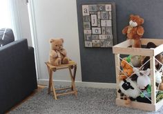 two teddy bears sitting on chairs in a living room next to a wall with letters