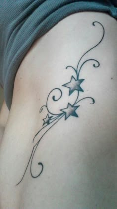 a woman's lower back tattoo with stars and swirls on the side,