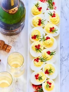 deviled eggs are arranged on a platter with garnishes and champagne