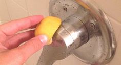 a person holding a lemon in front of a faucet