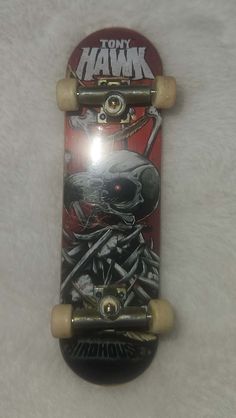 a skateboard with an image of a skull on the front and back wheels is laying on a white surface