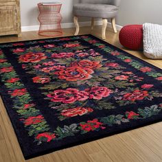 a black rug with red and pink flowers on it in front of a gray chair