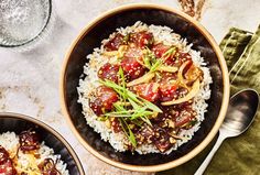 two bowls filled with rice and vegetables on top of a table next to silverware