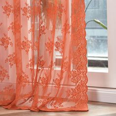 an orange lace curtain hanging in front of a window