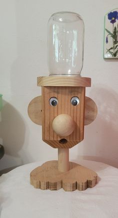 a wooden toy with a glass jar on top of it's head and eyes